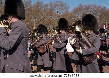 LONDON, UK - MARCH 19: Members of the Queen\'s Guard  band playing their instruments and marching into Buckingham Palace. March 19, 2011 in London UK.