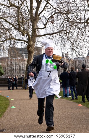 LONDON,UK-FEBRUARY 21: Lord Kennedy races for the Lords team in the annual Parliamentary Pancake Race, outside the Houses of Parliament on February 21, 2012 in London, UK.
