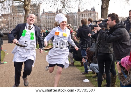 LONDON,UK-FEBRUARY 21: Lord Redesdale (left) and MP Tracey Crouch race past the crowds  in the 2012 Parliamentary Pancake Race, out side the Houses of Parliament on February 21, 2012 in London, UK