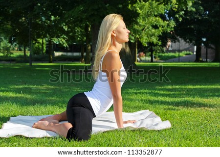 Young attractive girl does physical exercises in the park