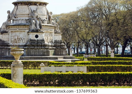 Old column base, angel statues, bas-relief and park in background, Empire Square, Belem, Lisbon, Portugal