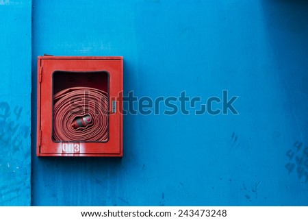 Fire hoses packed inside of red emergency box on the blue wall