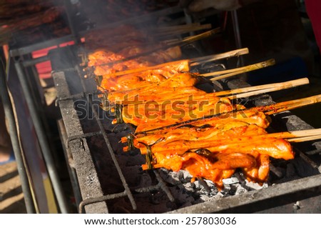 Thai street food grilled chicken on stove.
