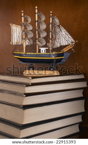 books on the shelf with  model  ship