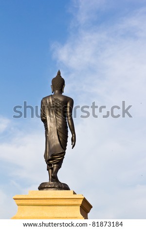 back of black buddha statue against blue sky in thai temple