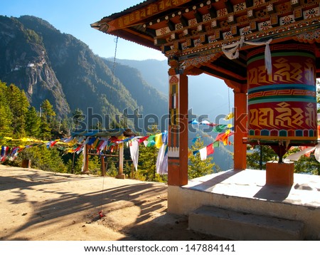 View of the Taktshang monastery in Paro (Bhutan) with prayer flags and a prayer wheel in the front
