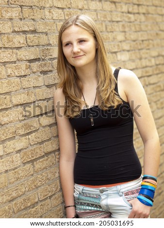 Young teenage girl looking sad or depressed in front of a brick wall background
