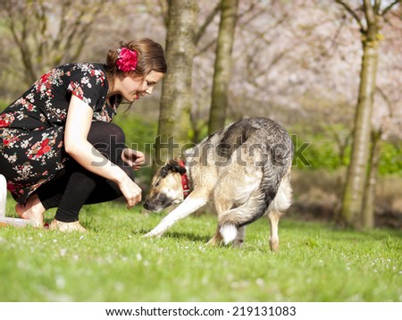 Beautiful girl having a picnic in the spring with her dog with blossoming trees in the background