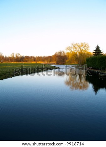 Landscape of a forest reflecting in the water with the setting sun lighting the trees