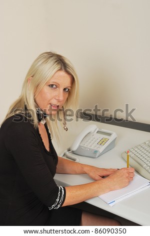 Secretary waiting to take notes at keyboard with phone