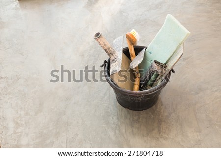 close up construction tools for concrete job in black plastic bucket on background of polished concrete surface