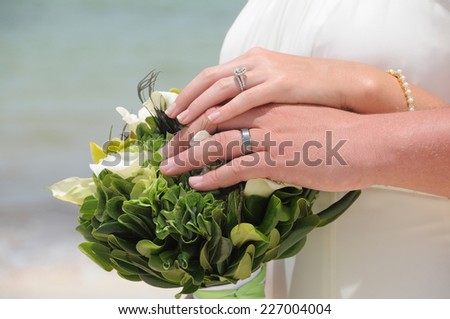 Close up of bride and groom putting their hands together on wedding bouquet