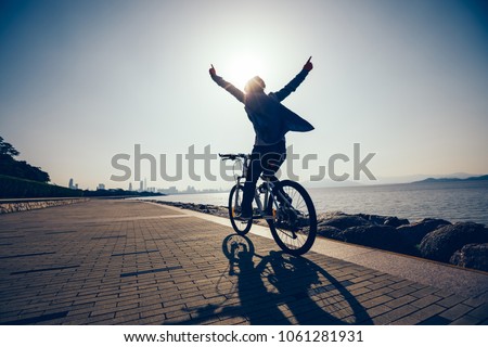 silhouette of happy cyclist riding bike in the sunrise coast