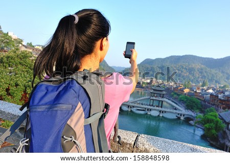 young asian woman use smart phone taking self photo at fenghuang ancient town,china