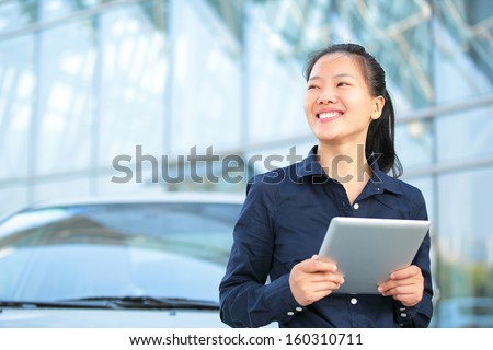 beautiful asian businesswoman use digital tablet leaning on car outside of office building