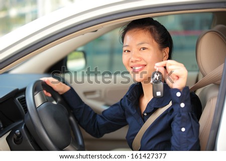 happy woman driver hold the car keys in her first car