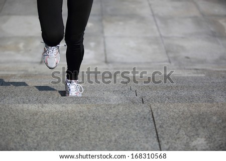 sports woman legs running up on stone stairs