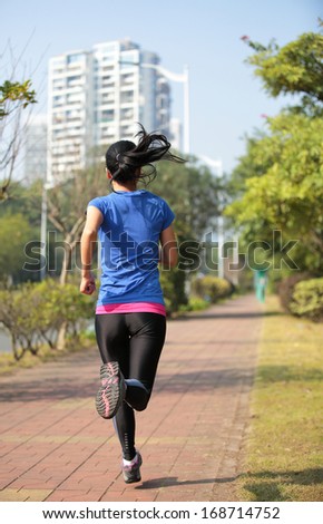 asian woman jogging at city pavement in the morning