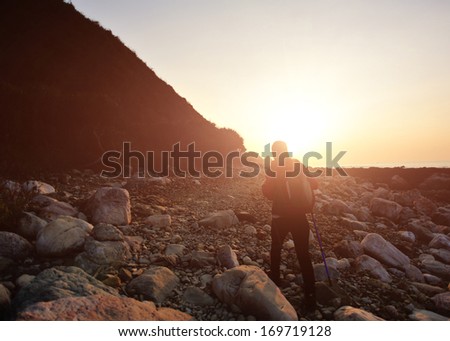 hiking woman hiking on stone beach to the sunrise at morning