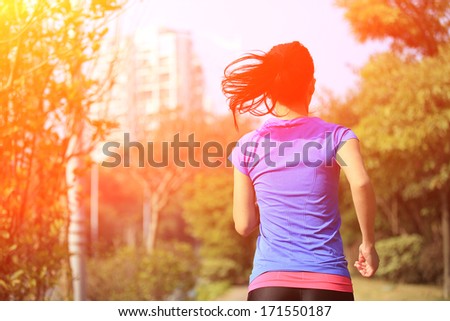 asian woman jogging at city pavement in the morning