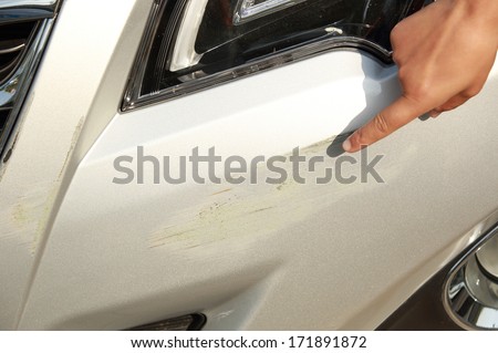 finger point at scratches on front bumper after accident of a car