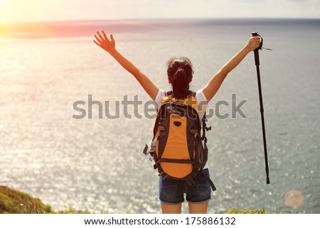 cheering woman hiker open arms to the sea at seaside