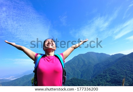 woman climber on mountain peak with arms open