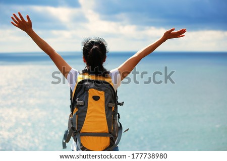 happy cheering asian woman hiker open arms to sea