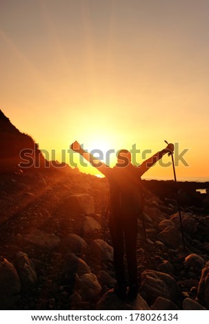 cheering hiking woman raised arms to the sunrise in the morning at seaside