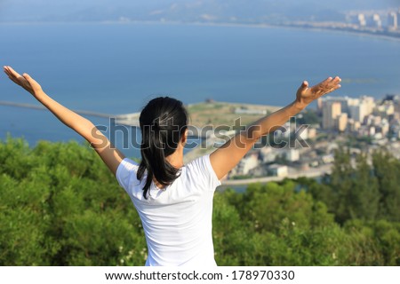 cheering woman stand mountain peak open arms to sea