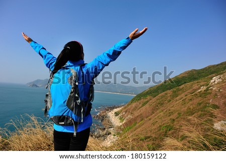 cheering hiking woman stand seaside rock looking the view with arms open