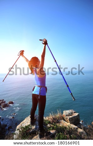 hiking woman stand seaside rock looking the view with arms open