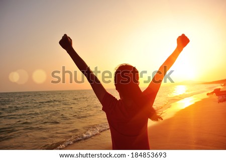 cheering woman open arms at sunset seaside beach