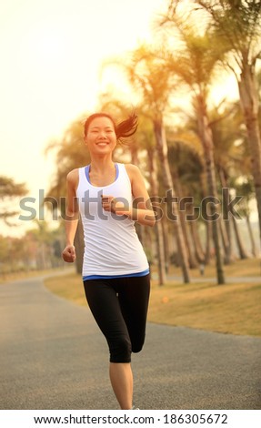Runner athlete running at tropical park. woman fitness jogging  workout wellness concept.