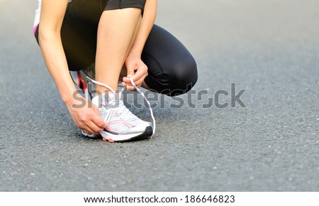 young woman in fitness wear ties shoelaces outdoors