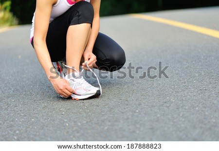 young fitness  woman  tying shoelaces on road
