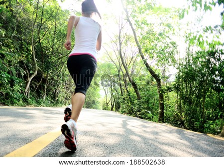 Runner athlete running at forest road. woman fitness jogging workout wellness concept.