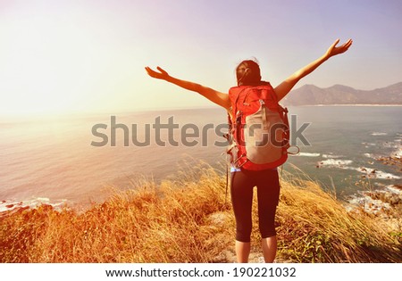 cheering hiking woman stand mountain peak looking at the view with arms open