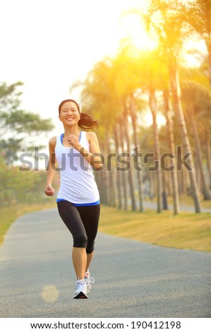 Runner athlete running at tropical park road. woman fitness jogging workout wellness concept.
