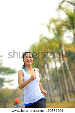 Runner athlete running at tropical park road. woman fitness jogging workout wellness concept.