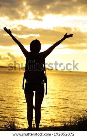 cheering woman hiker open arms to the sunrise stand at seaside