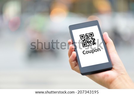 woman hand hold smart phone with coupon QR code in modern city