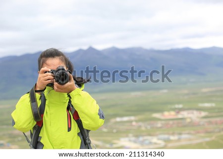 woman photographer taking photo at plateau mountain peak in tibet,china