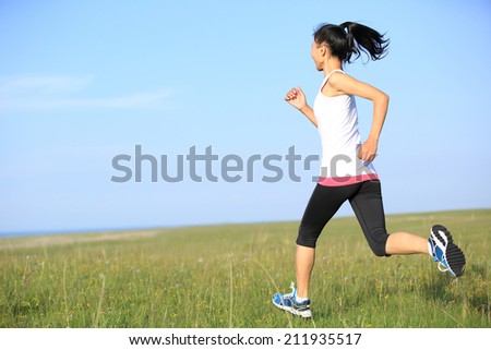 Runner athlete running on grass seaside. woman fitness  jogging workout wellness concept.