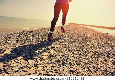 Runner athlete running on stone beach of qinghai lake. woman fitness jogging workout wellness concept.