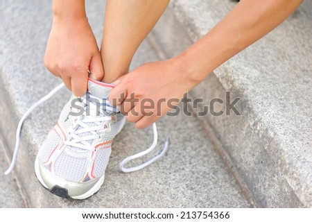 young  woman runner tying shoelaces on stairs