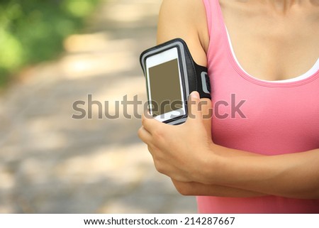 Runner athlete listening to music from smart phone mp3 player smart phone armband.woman fitness jogging workout wellness concept.