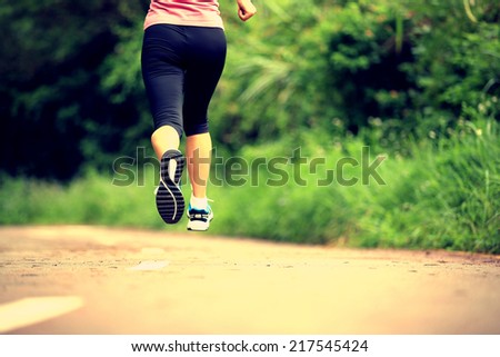 young fitness woman legs running at forest trail