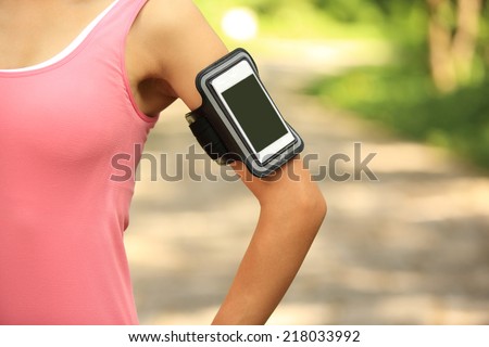 Runner athlete listening to music from smart phone mp3 player smart phone armband.woman fitness jogging workout wellness concept.