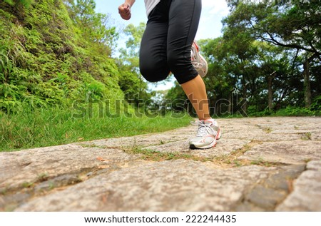 young fitness woman legs running at forest stone trail
